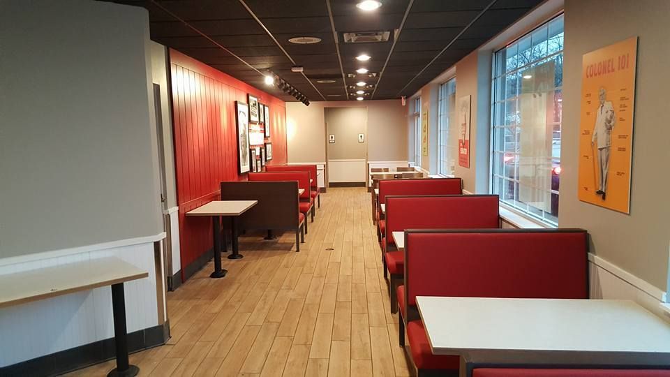 Interior of a fast-food restaurant with red booths, wooden floor, and a row of tables.