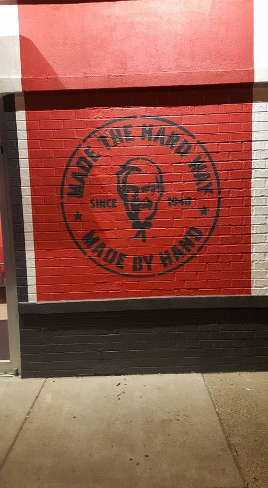 KFC mural on red brick wall with Colonel Sanders logo and text: 