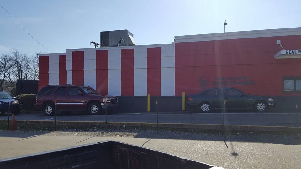 Red and white striped building with vehicles parked in front.