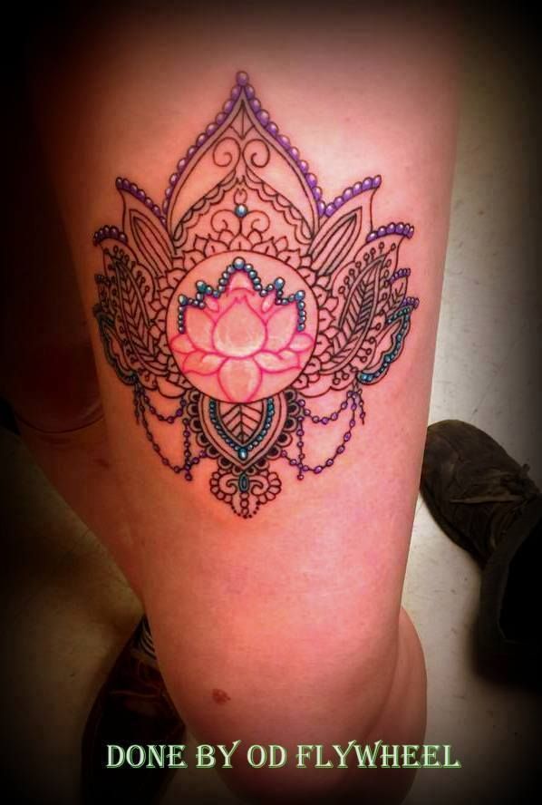 Lotus flower tattoo on a thigh, with intricate details in pink, blue, and purple.