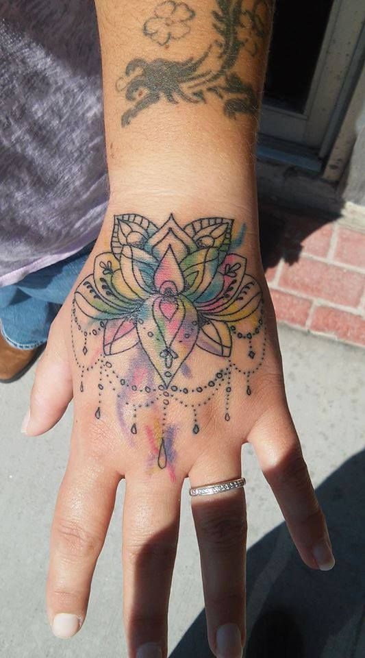Hand with colorful lotus flower tattoo.