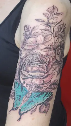 Tattoo of roses and a turquoise butterfly on an arm.
