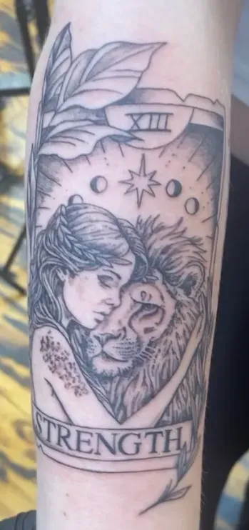 Tattoo of a woman embracing a lion.