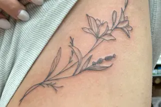 A gray outline tattoo of a lily and lavender sprig on skin.