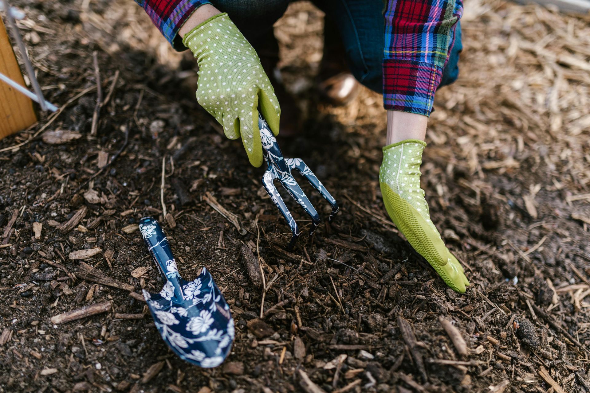 Person in gloves gardening with hand tools.