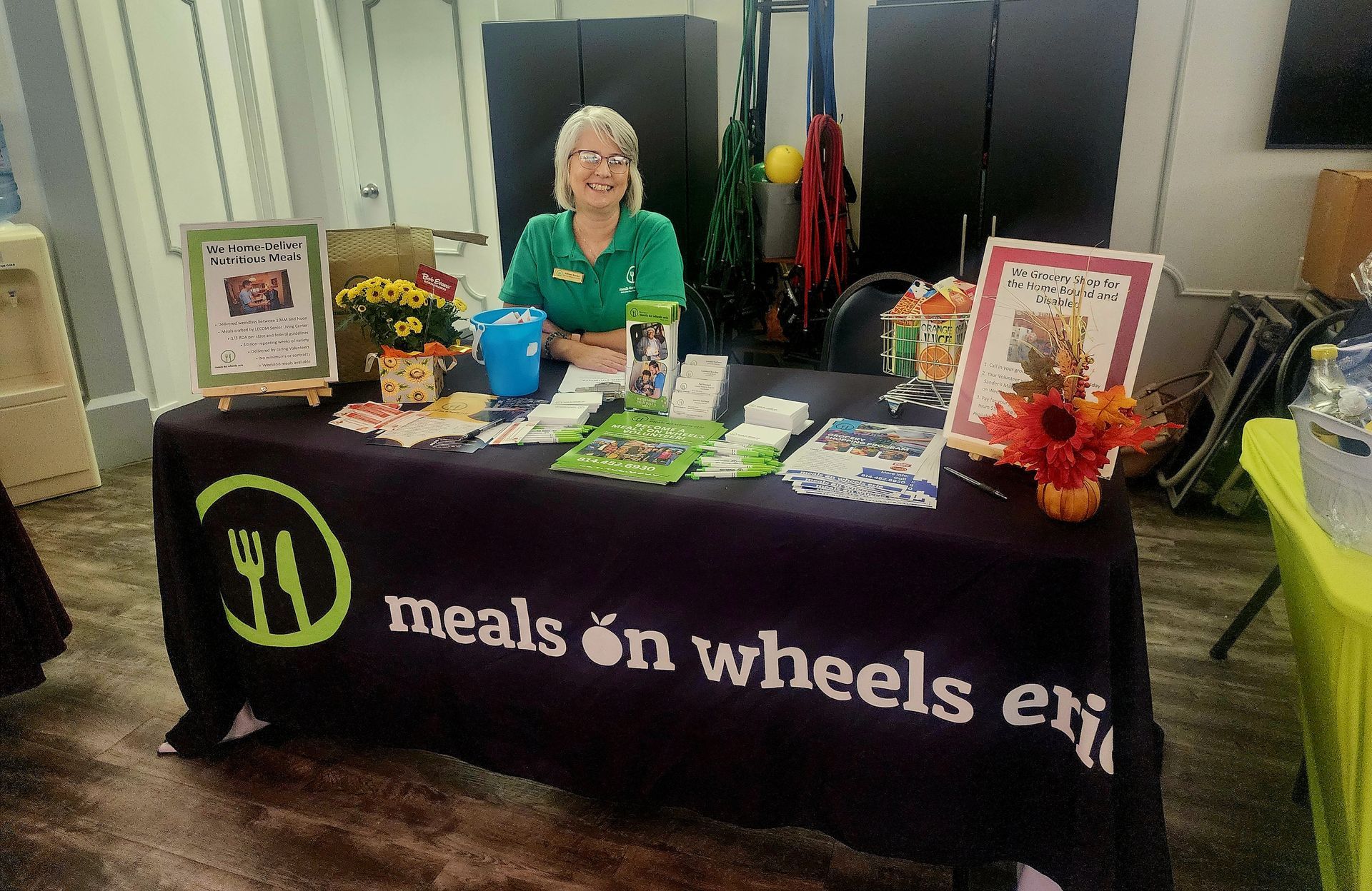 A woman is sitting at a table that says meals on wheels