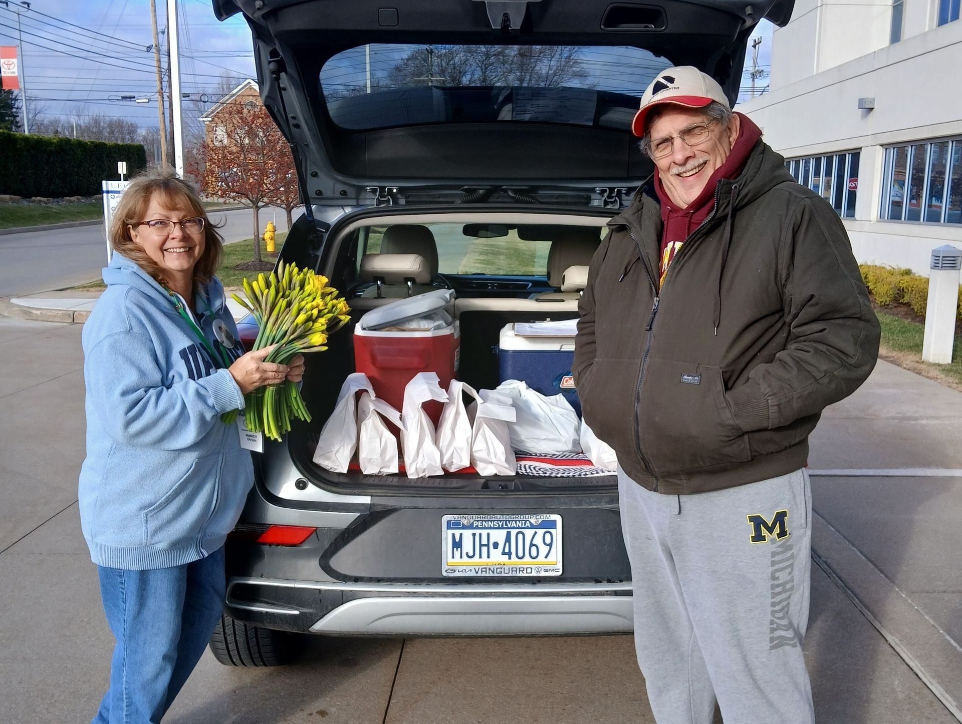 A man and woman standing next to a car with a michigan license plate