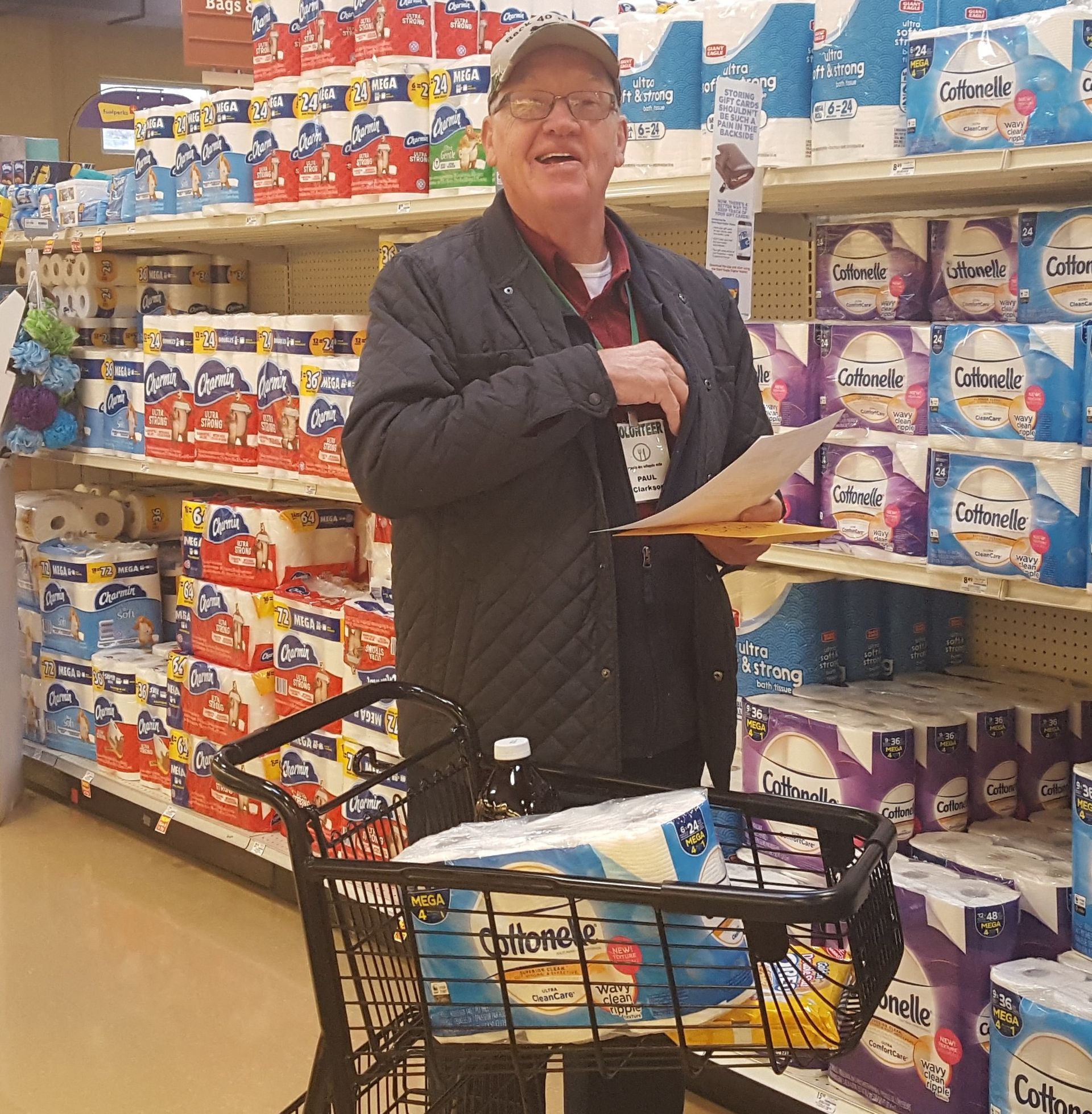 A man in a store with a cart full of toilet paper