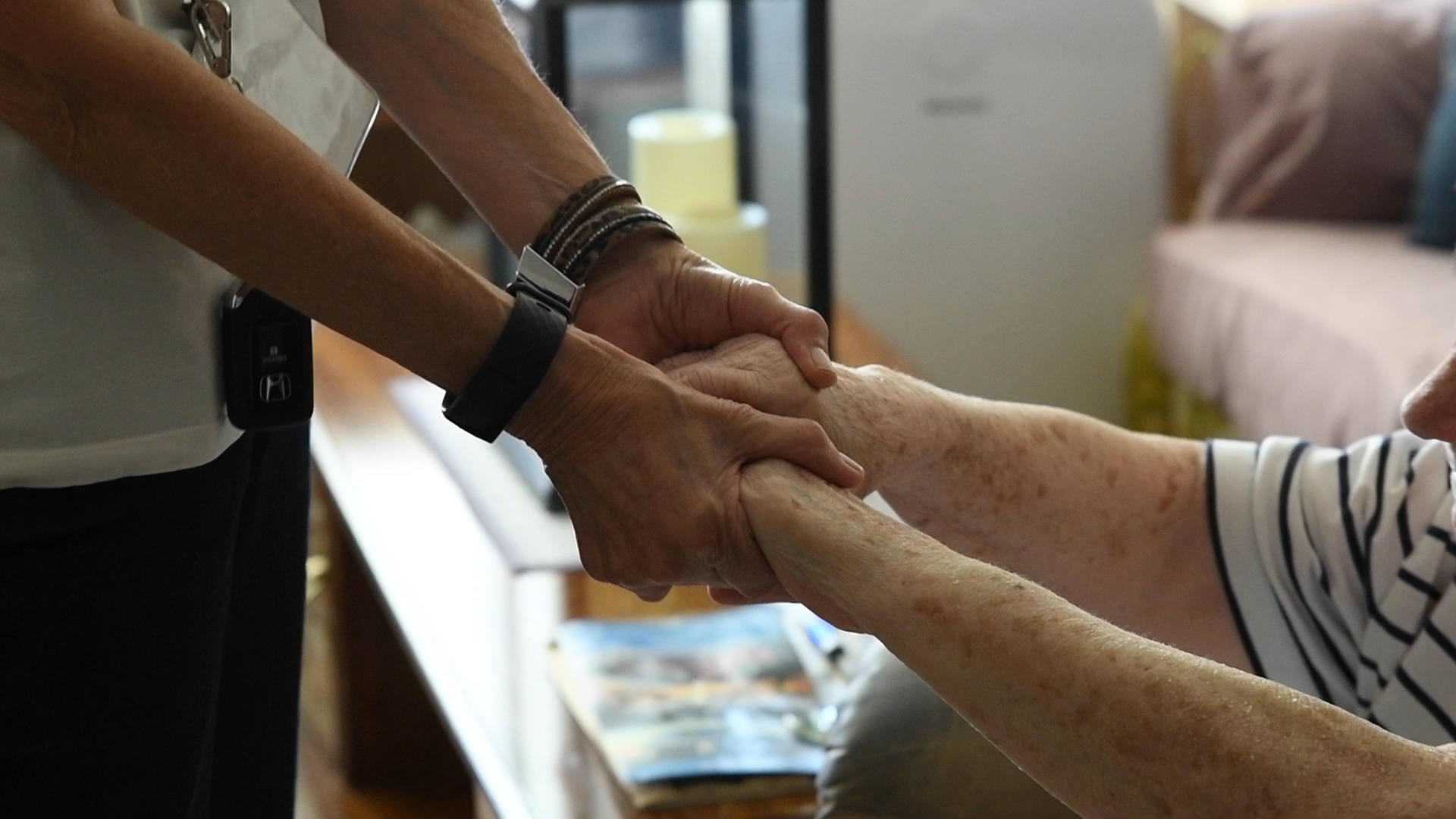 A woman is holding the hand of an older woman.