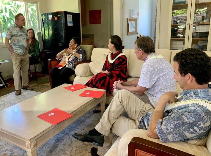 A group of people are sitting around a coffee table in a living room.