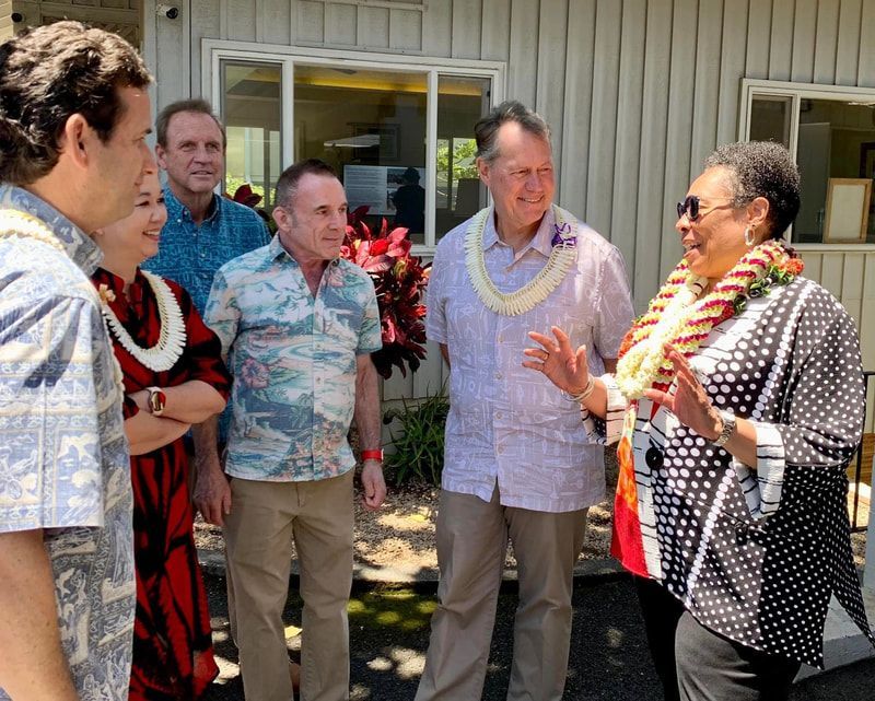 A group of people standing in front of a house talking to each other