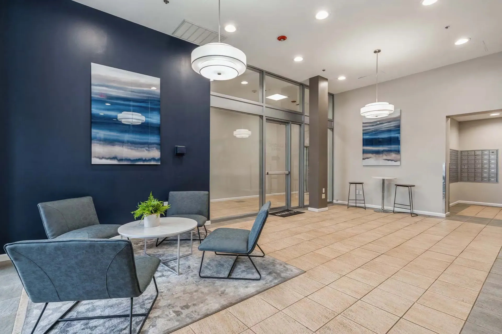Modern apartment lobby with blue accent wall, seating, and glass doors Parc at Lyndhurst in Lyndhurst, NJ.