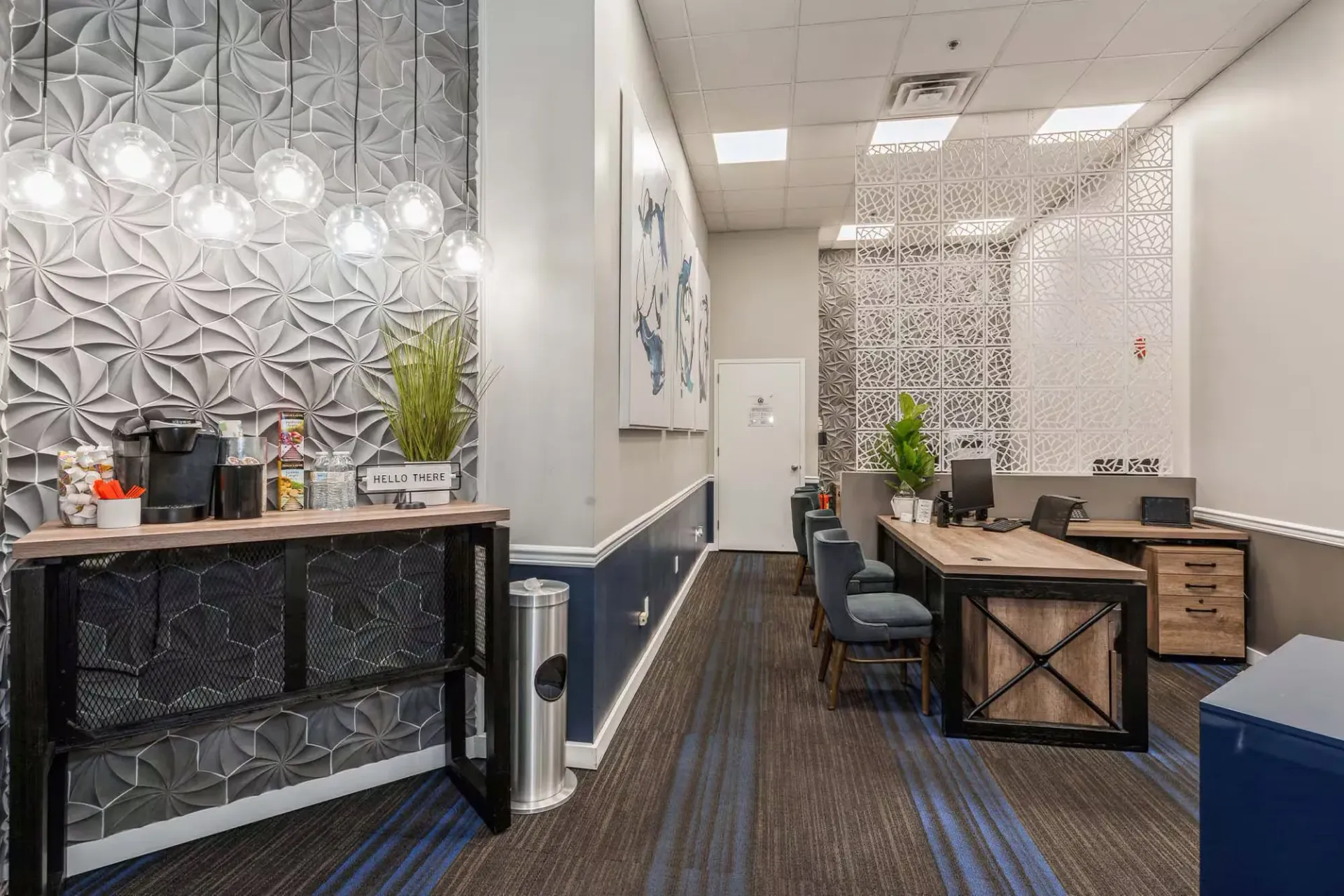 Leasing office lobby with coffee station, geometric wall texture, and workstation desks Parc at Lyndhurst in Lyndhurst, NJ.