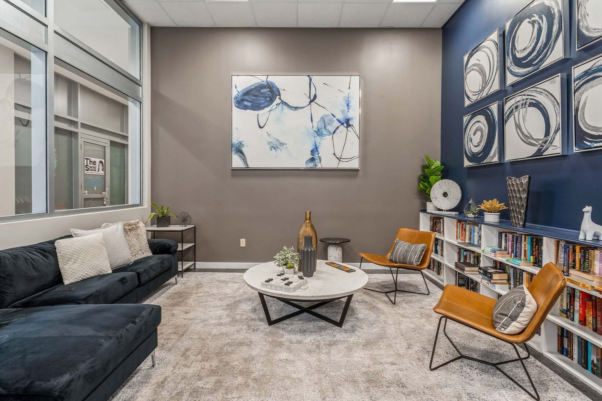 Cozy communal lounge with sofa, chairs, coffee table, and bookshelves Parc at Lyndhurst in Lyndhurst, NJ.