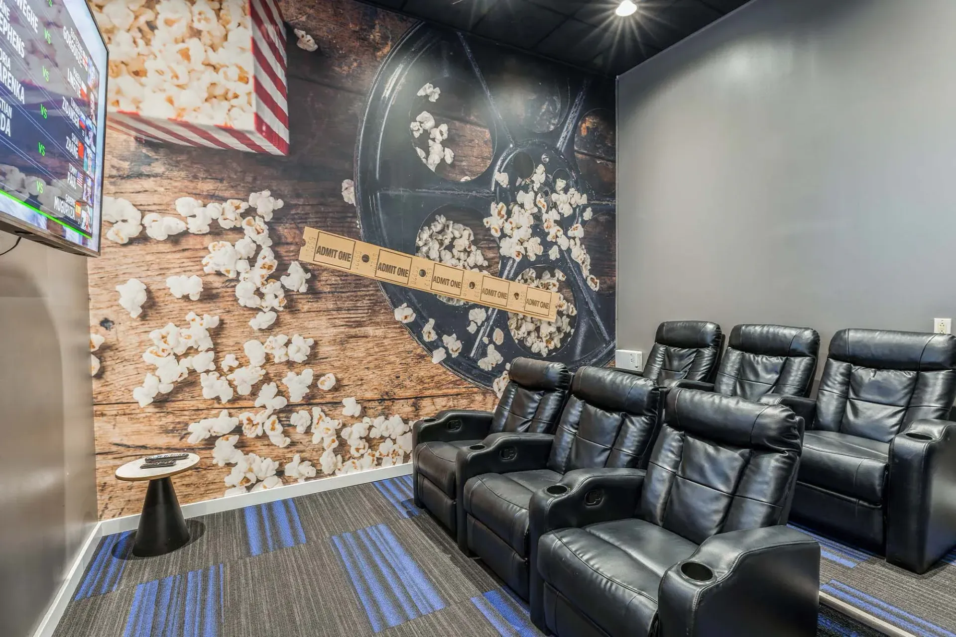 Indoor cinema room with black leather recliners and a popcorn-themed wall mural Parc at Lyndhurst in Lyndhurst, NJ.