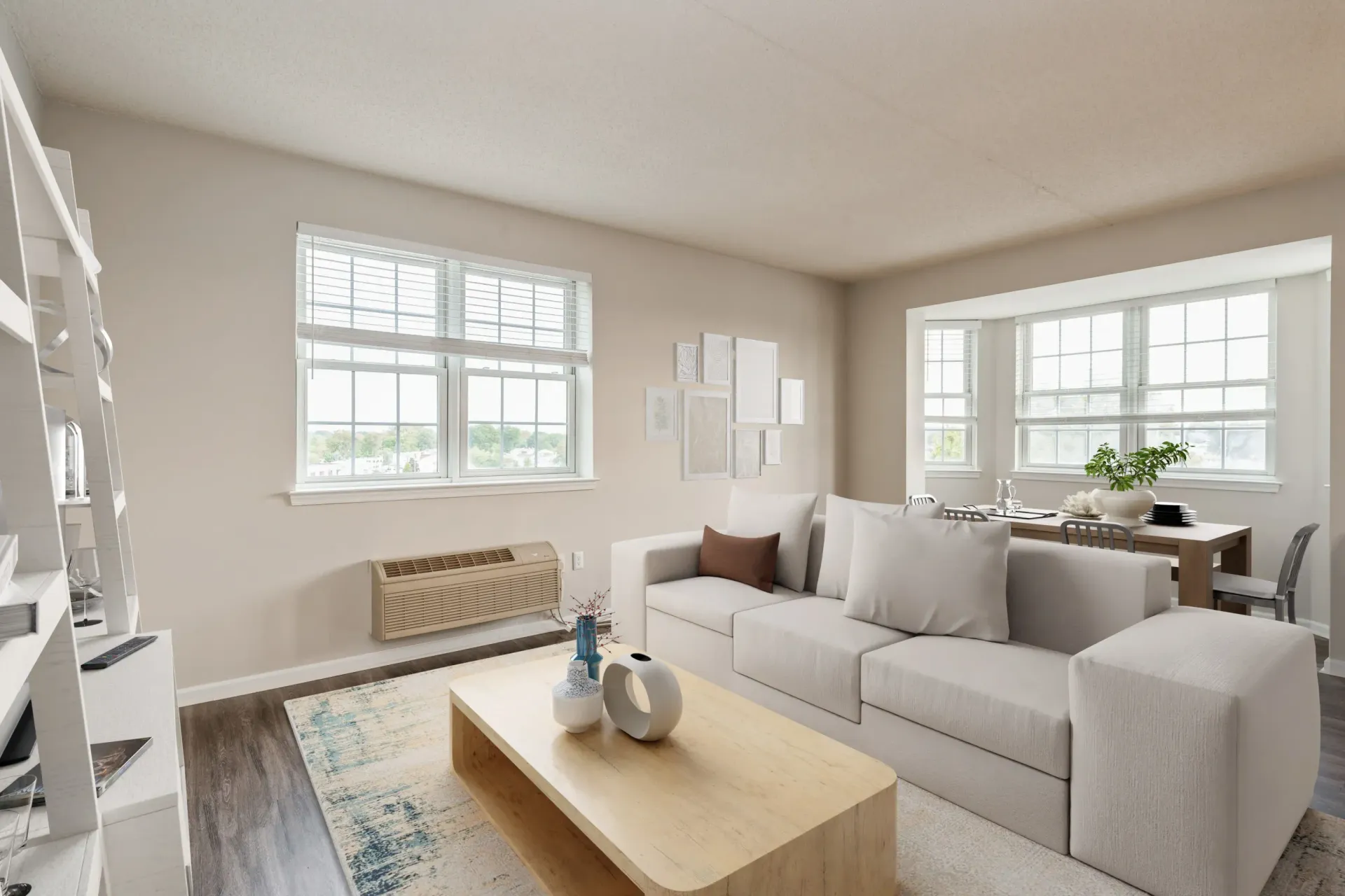 Bright apartment living room with a white sectional sofa, light wood coffee table, and large grid windows Parc at Lyndhurst in Lyndhurst, NJ.