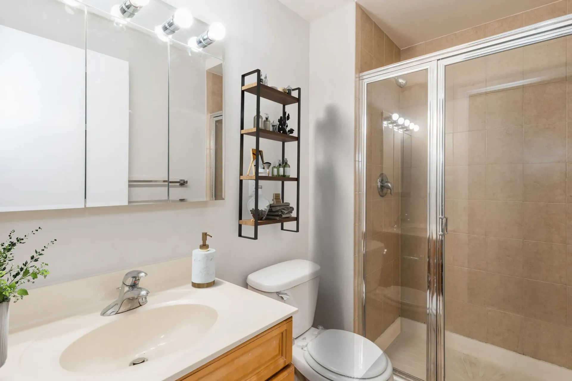 Modern apartment bathroom with vanity, mirror cabinet, open shelf, toilet, and glass shower Parc at Lyndhurst in Lyndhurst, NJ.