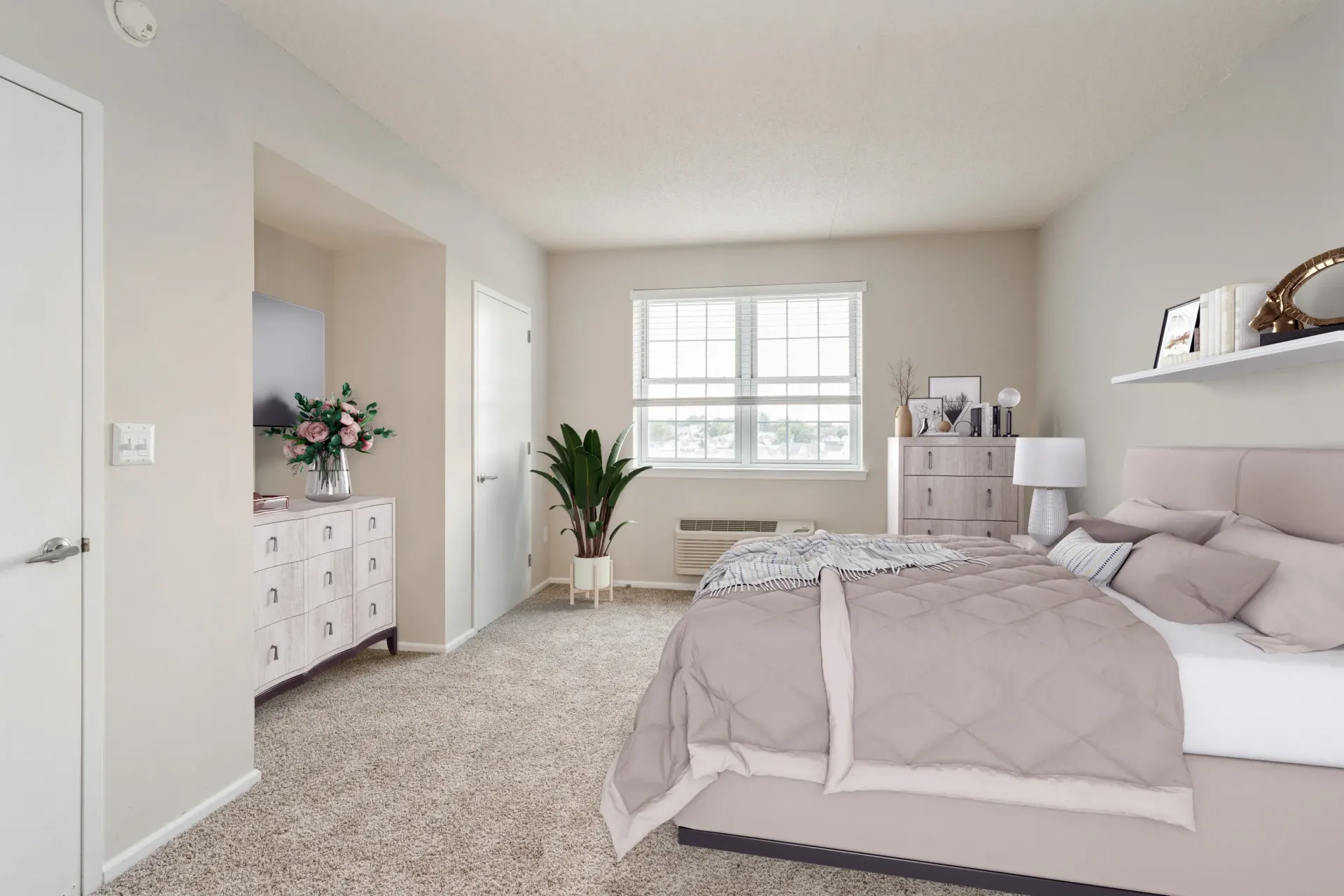 Furnished apartment bedroom with a queen bed, dresser, plants, and a large window Parc at Lyndhurst in Lyndhurst, NJ.