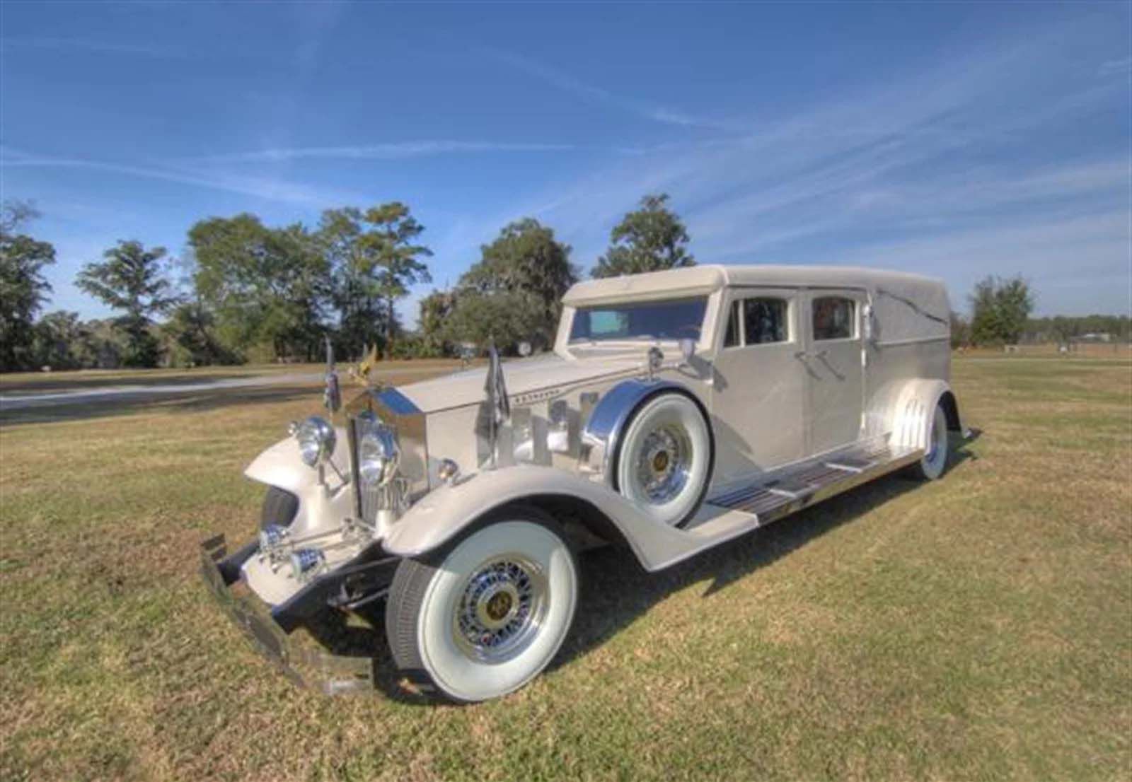 A white car with white tires is parked in a grassy field.