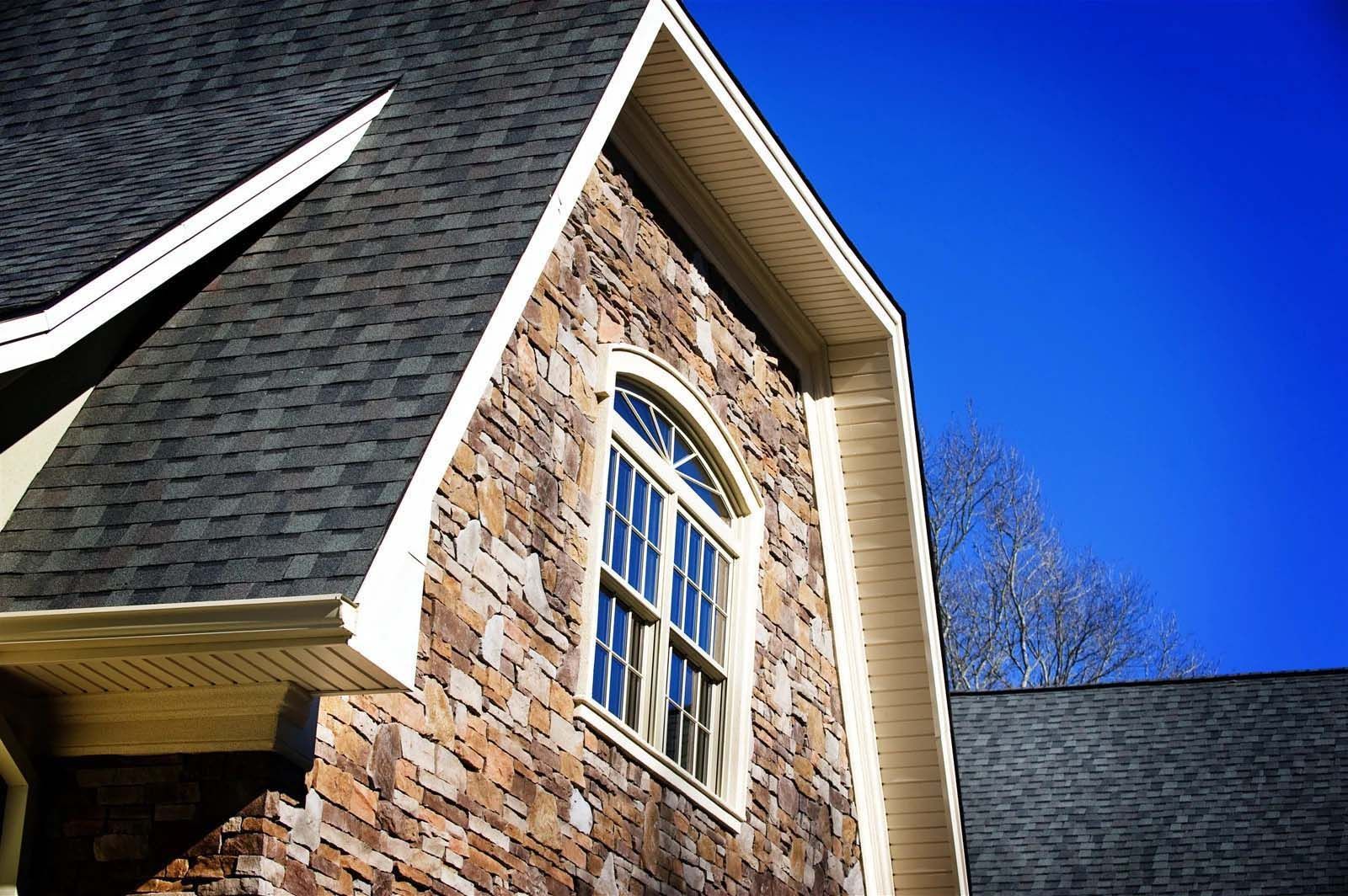 A brick building with a window and a black roof
