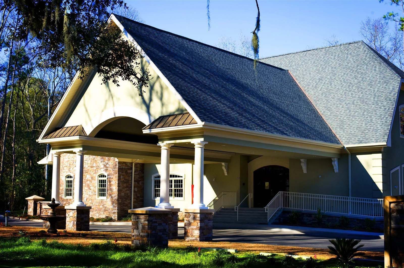 A large house with a gray roof is surrounded by trees