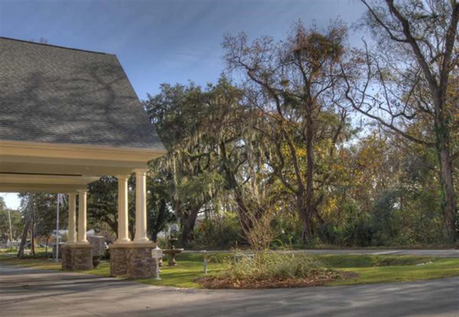 A large white building with a porch and trees in the background.