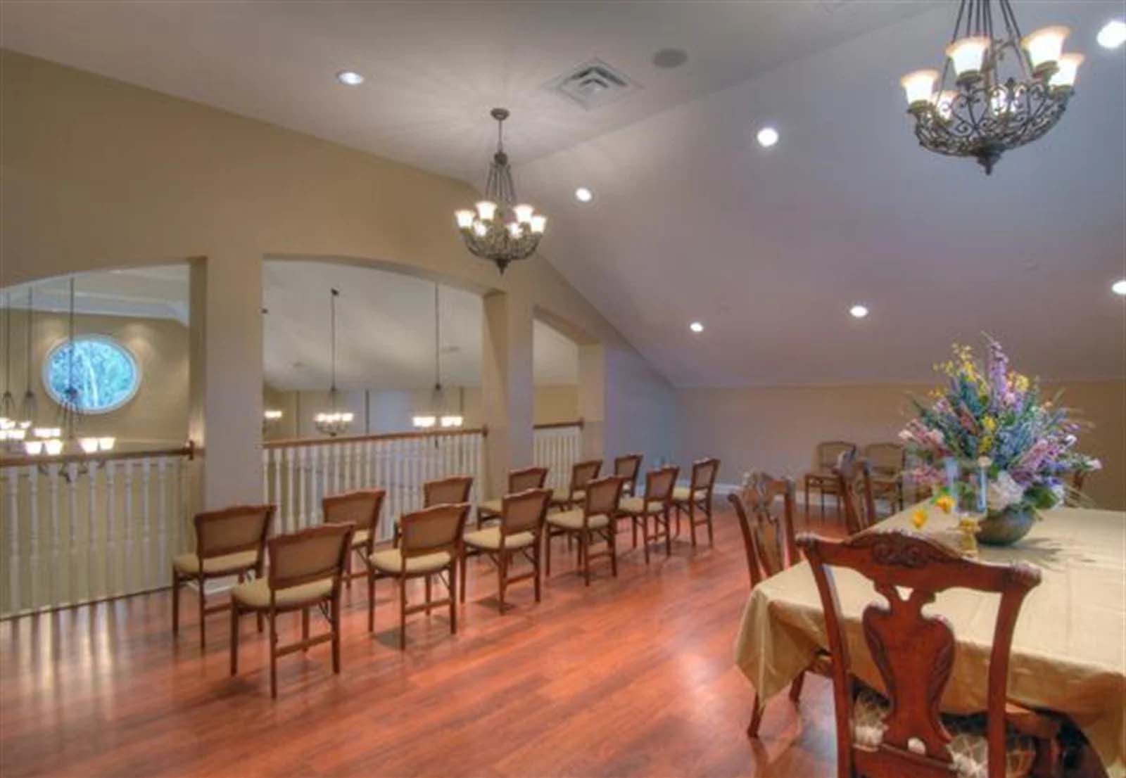 A room with a table and chairs and a vase of flowers.