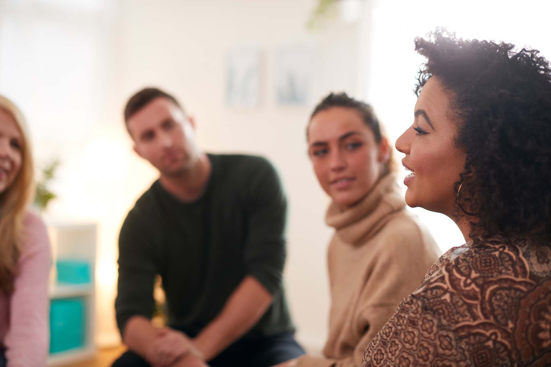 A group of people are sitting in a circle talking to each other.