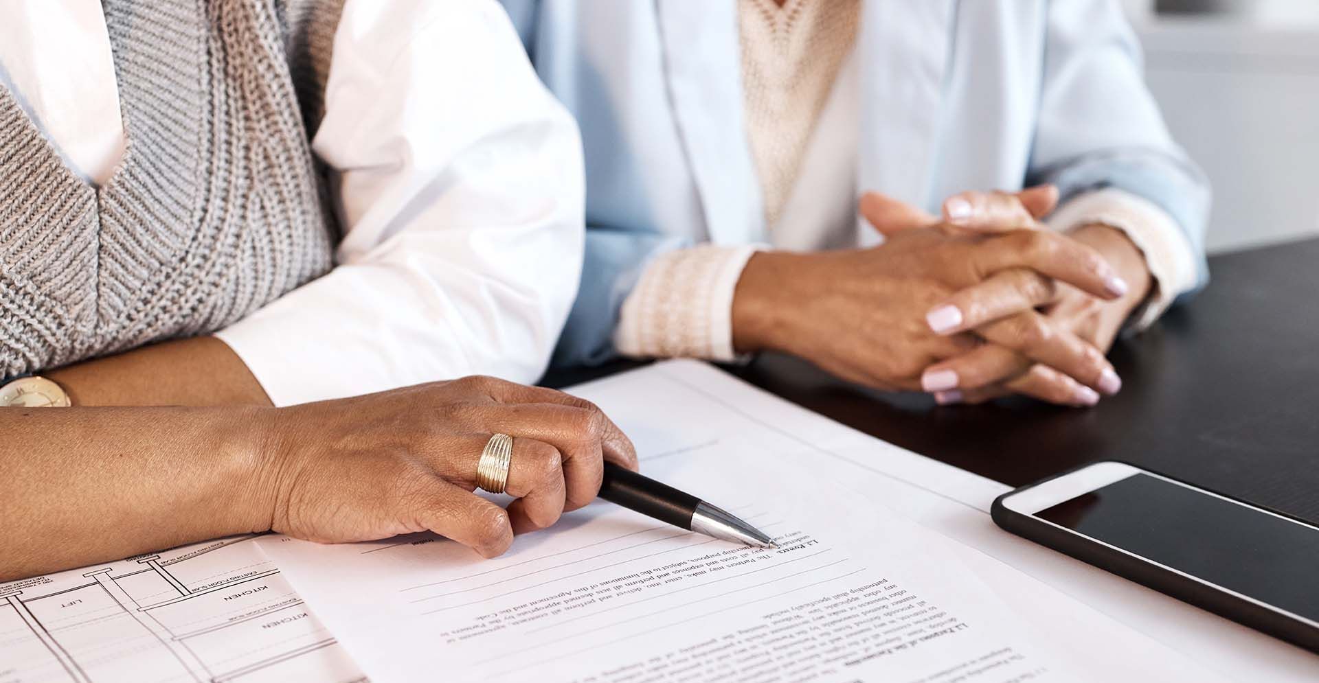 Two women are sitting at a table looking at a piece of paper.