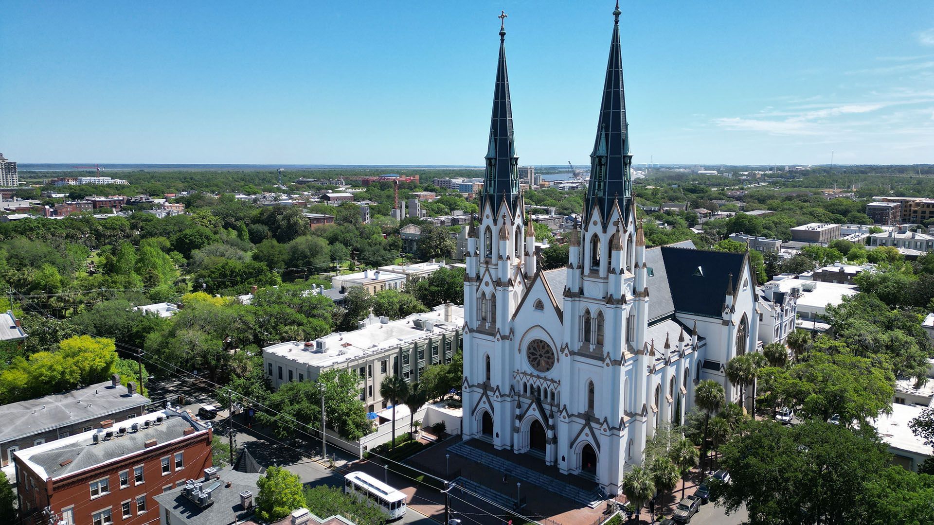 An aerial view of a large white cathedral surrounded by trees in a city.