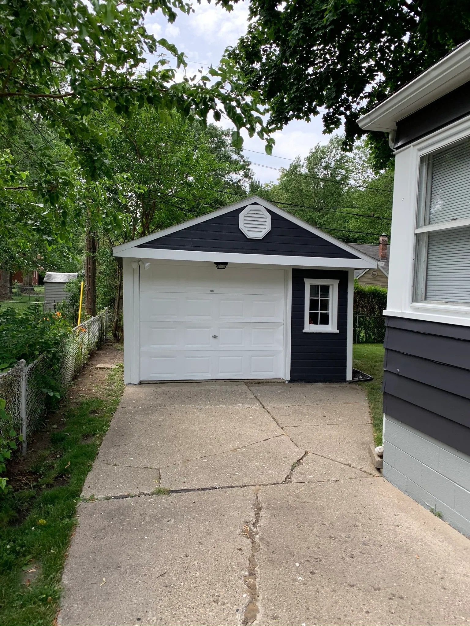 Woman in straw hat smiles, holding wine glass near a lake.