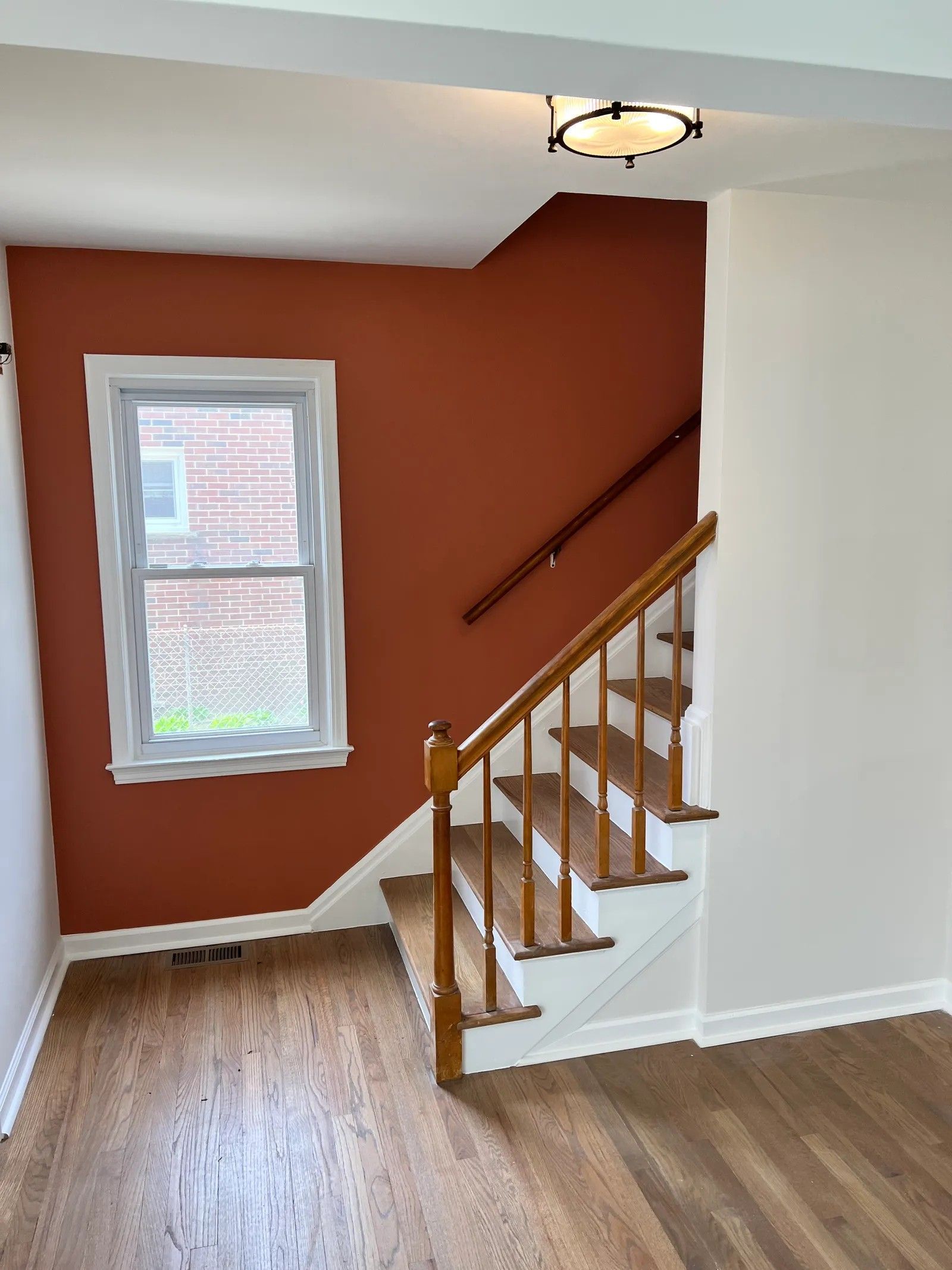 Woman in straw hat smiles, holding wine glass near a lake.
