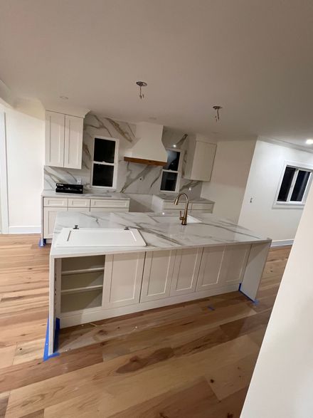 Newly renovated kitchen with white cabinets, marble countertops, and wooden floors.