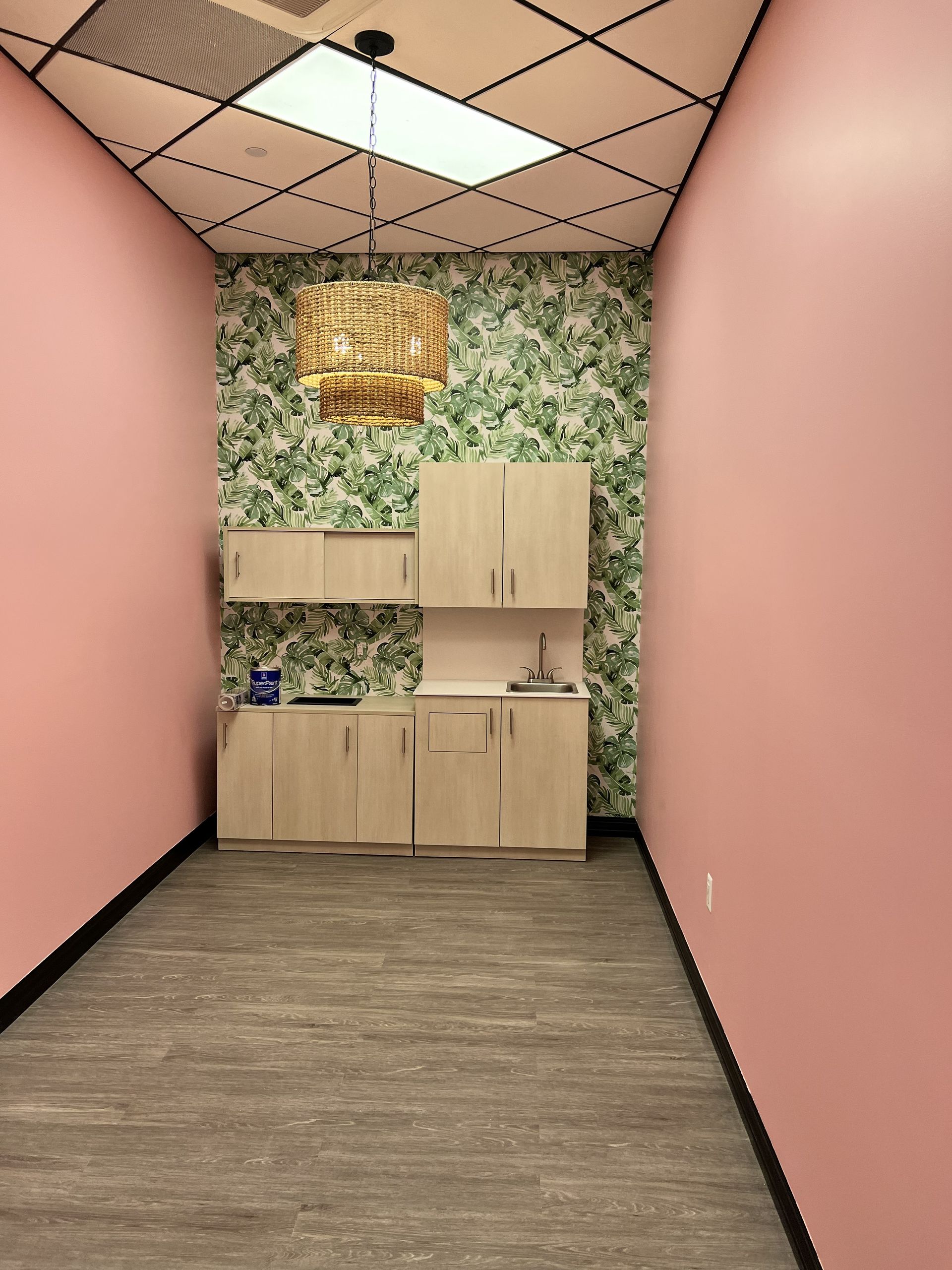Woman in straw hat smiles, holding wine glass near a lake.