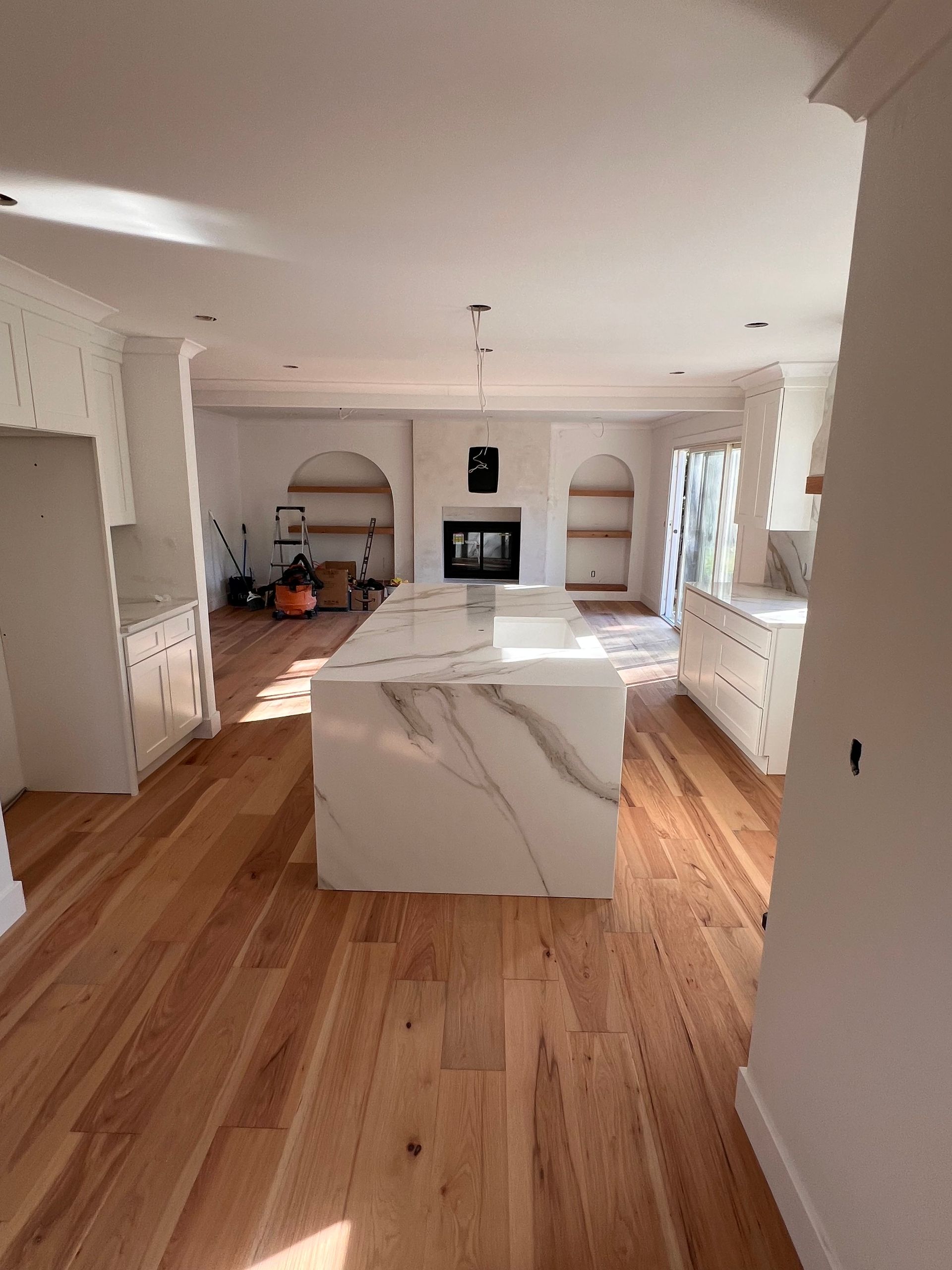 Woman in straw hat smiles, holding wine glass near a lake.