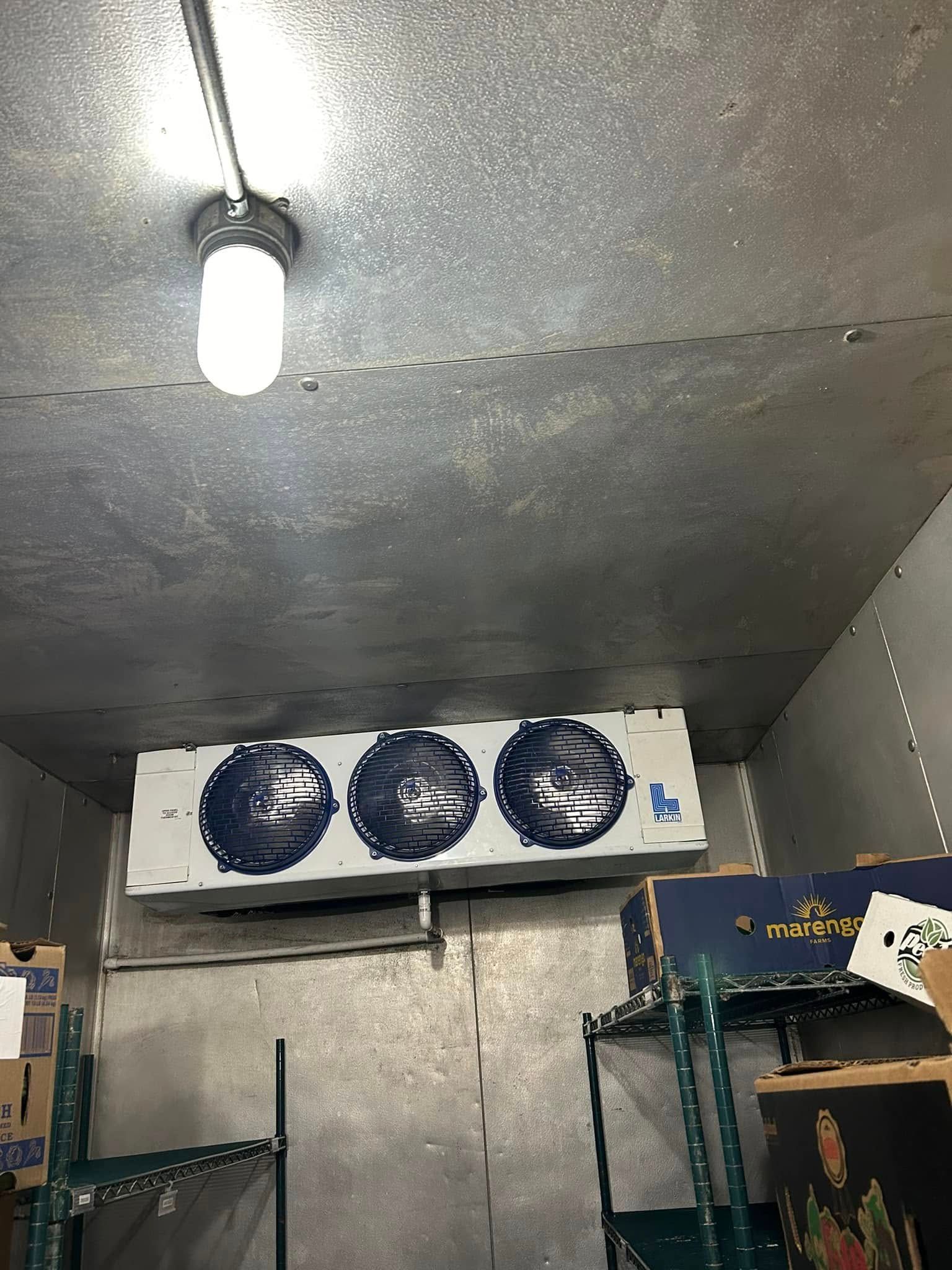 A refrigerator with boxes on shelves and a light on the ceiling.