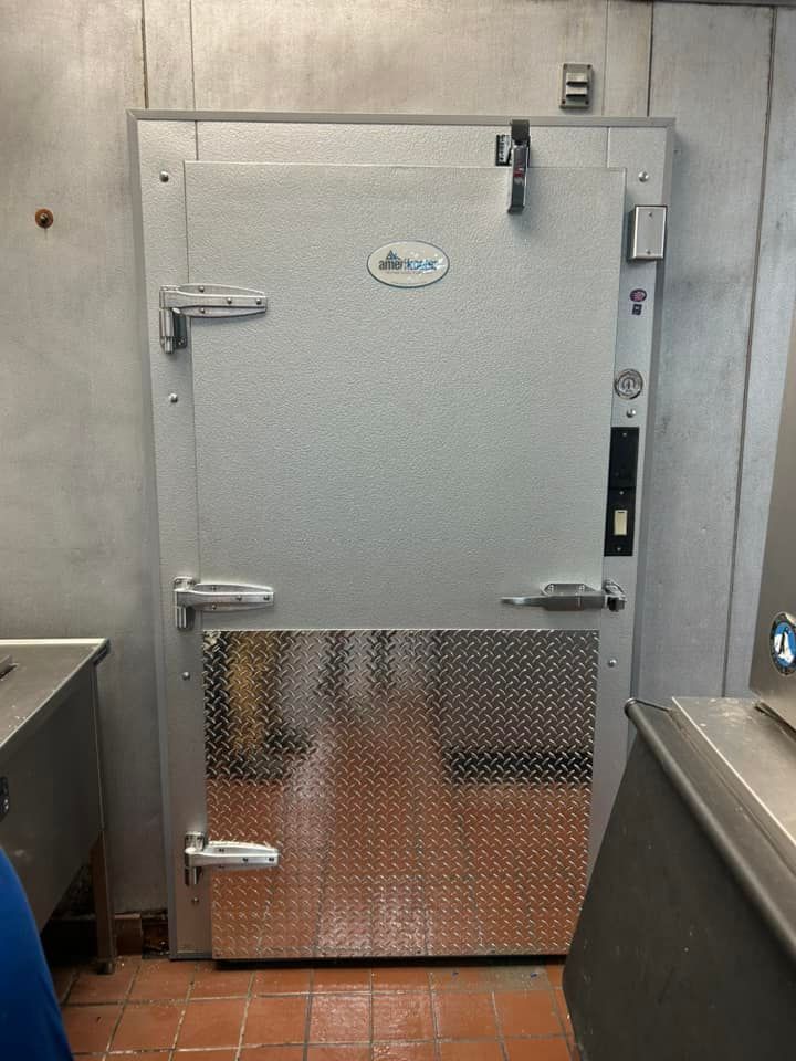 A stainless steel door is in a room with a tiled floor.
