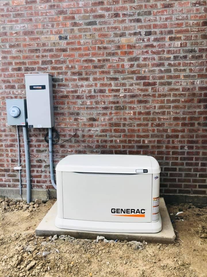 A generator is sitting in front of a brick wall.