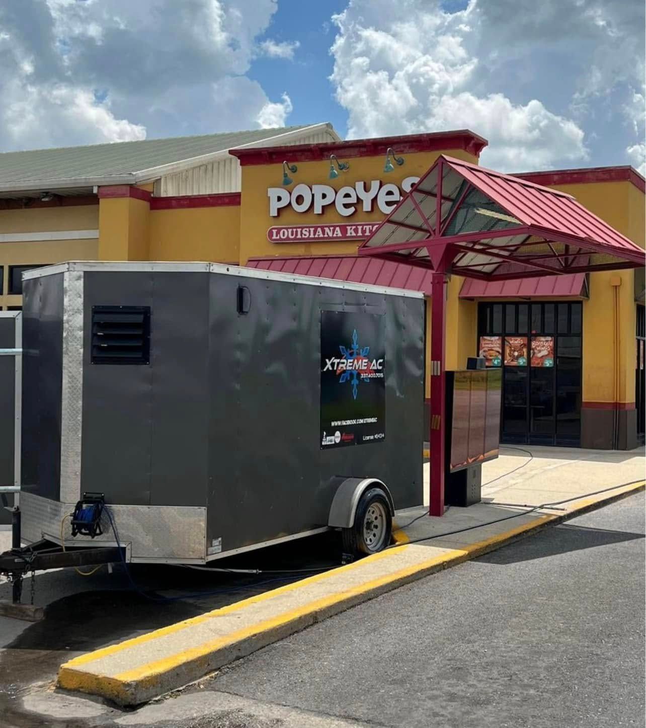 A popeye restaurant with a trailer parked in front of it