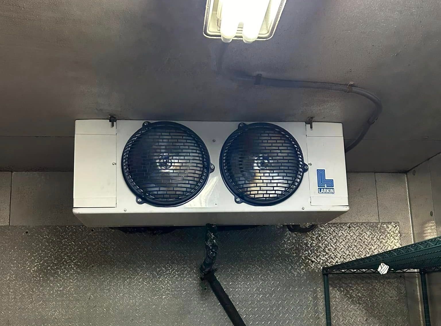 Two fans are hanging from the ceiling of a room.