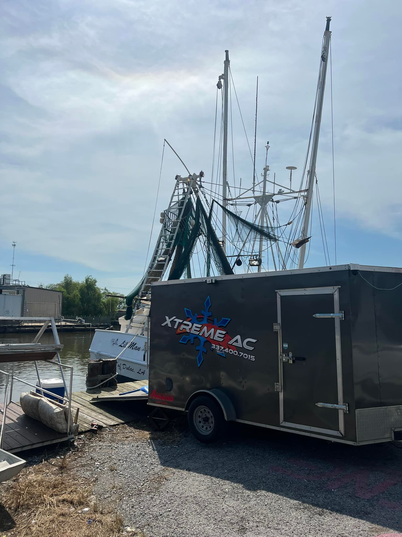 A trailer is parked in a gravel lot next to a boat.