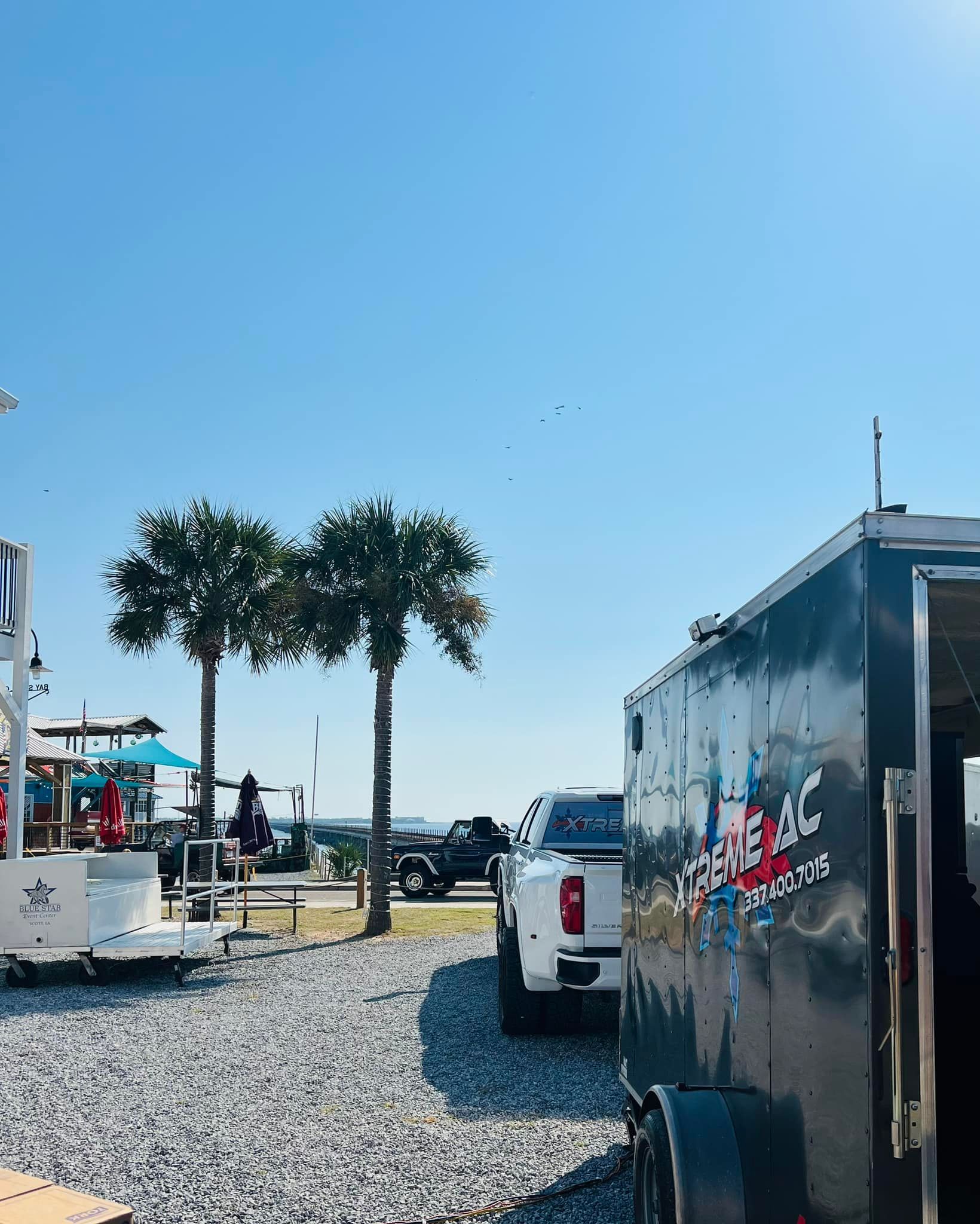 A truck is parked in a gravel lot next to a trailer.