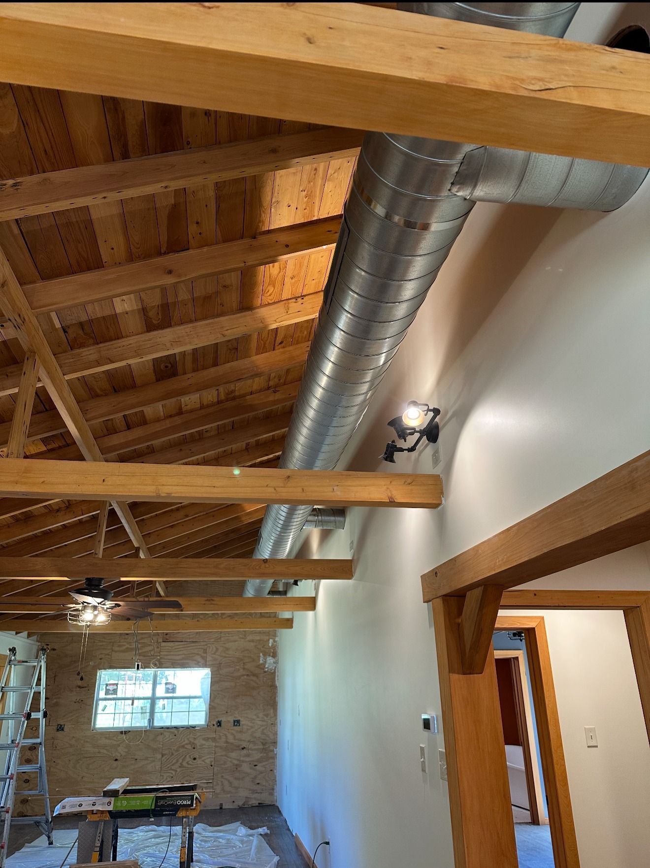 A room with a wooden ceiling and a metal pipe hanging from the ceiling.