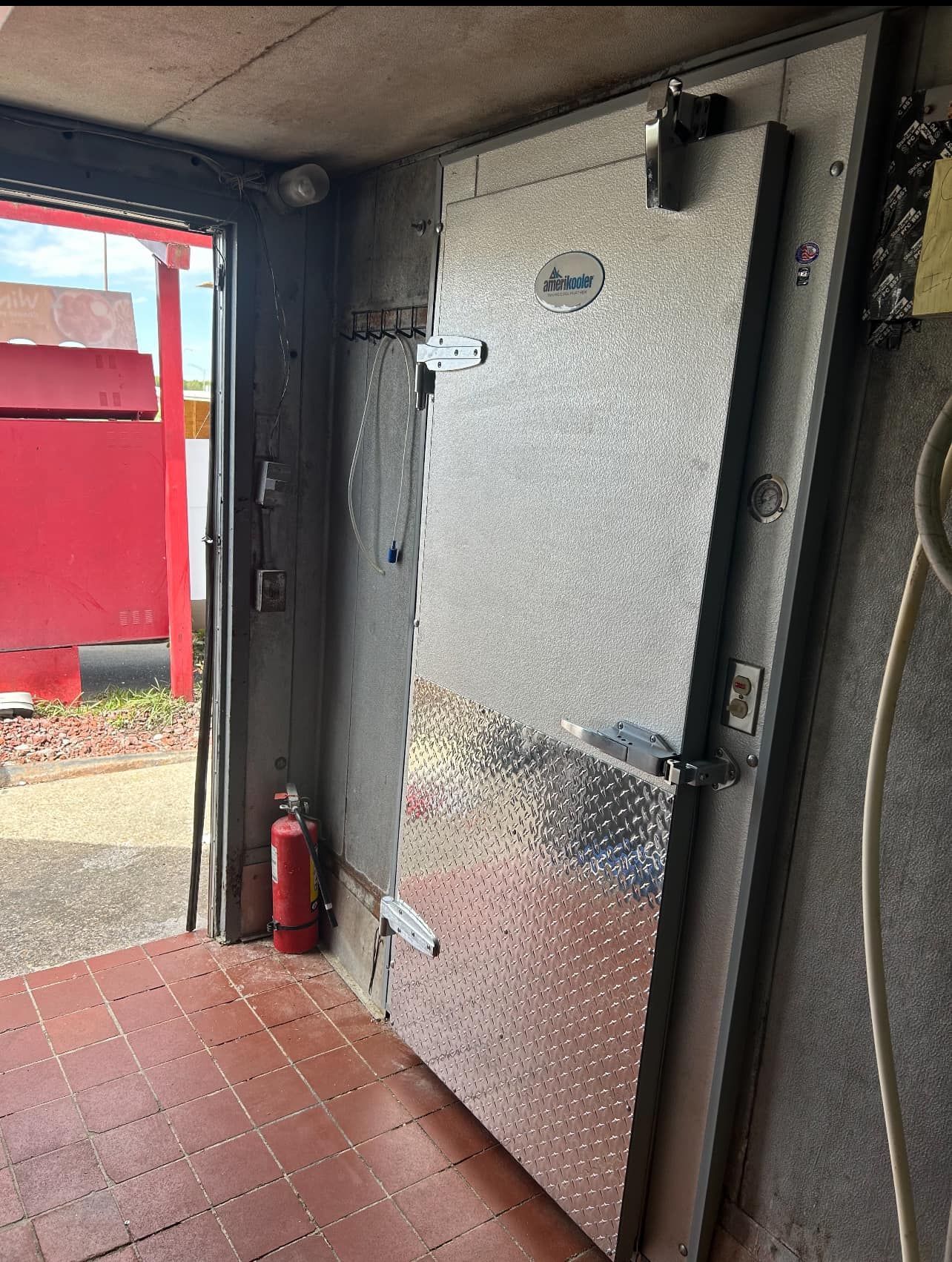 A fire extinguisher is sitting next to a door in a room.