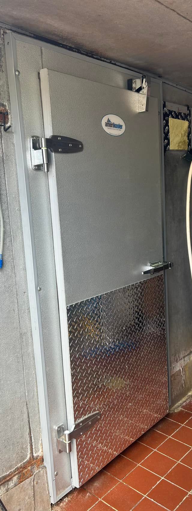 A refrigerator door is open in a room with a tiled floor.