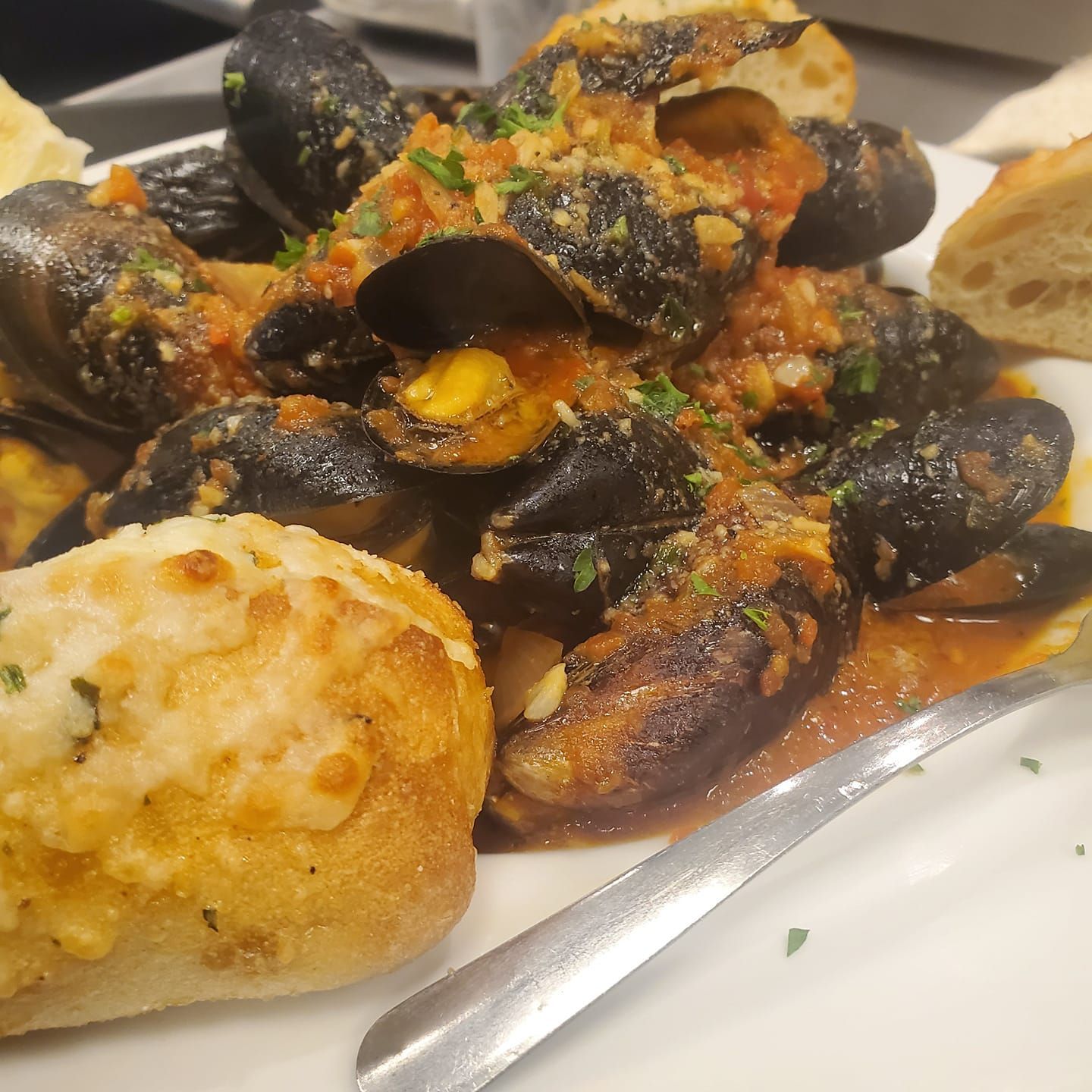 A white plate topped with mussels and garlic bread