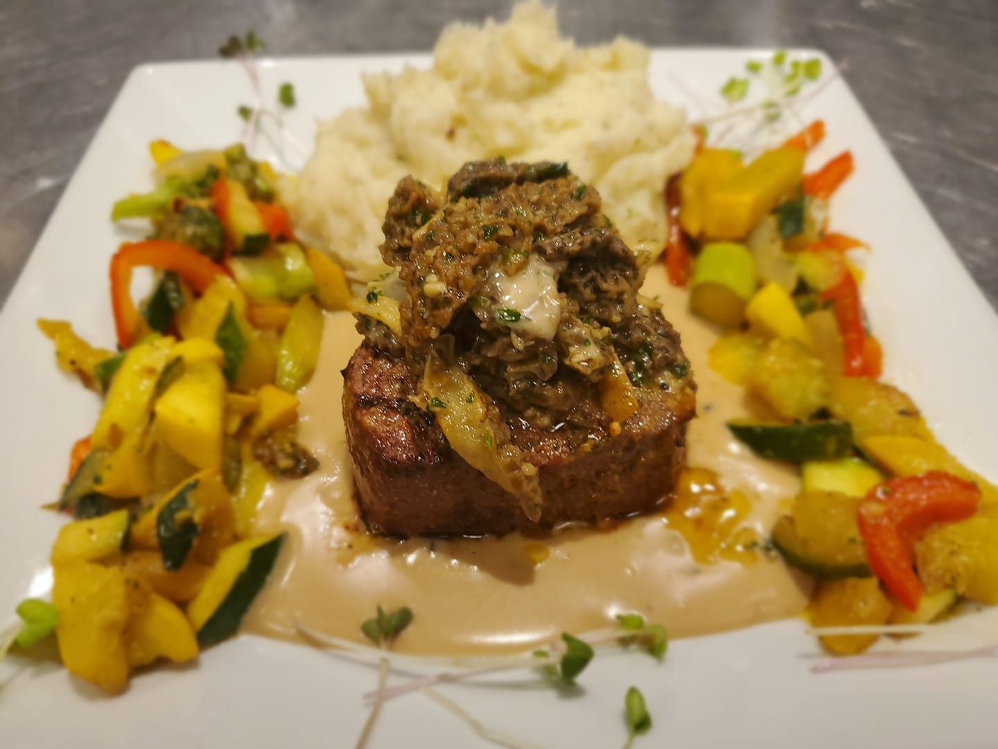 A white plate topped with meat , mashed potatoes and vegetables.