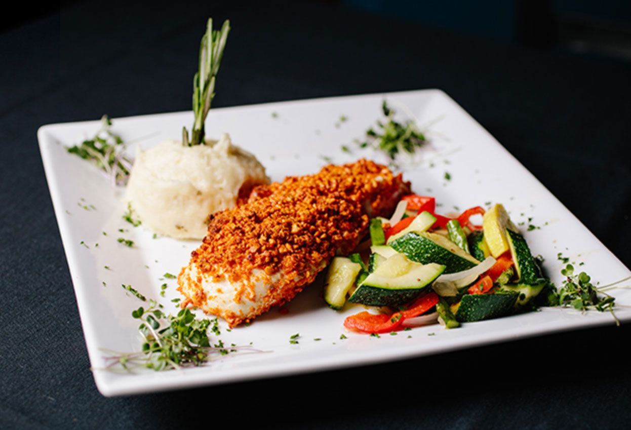 A white plate topped with meat and vegetables on a table.