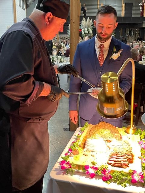A man in a suit and tie is cutting a cake