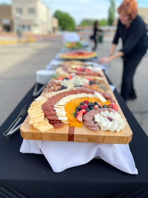 A long wooden cutting board filled with meats and cheeses